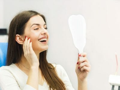 woman looking in the mirror and happy to see her nice smile