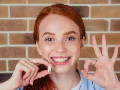 woman holding a tooth extraction with a smile