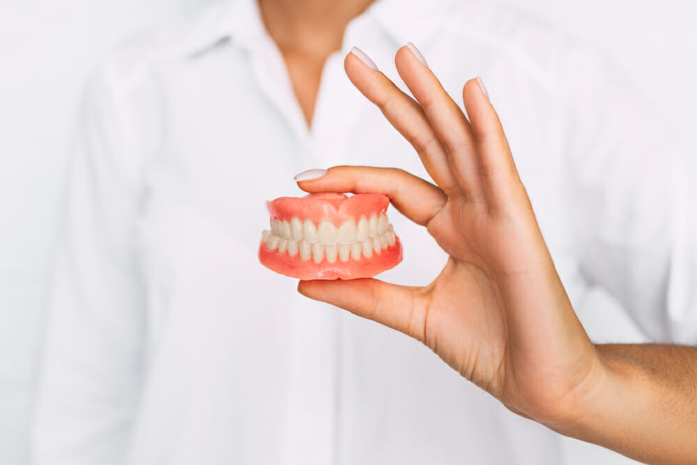 Person holding set of dentures