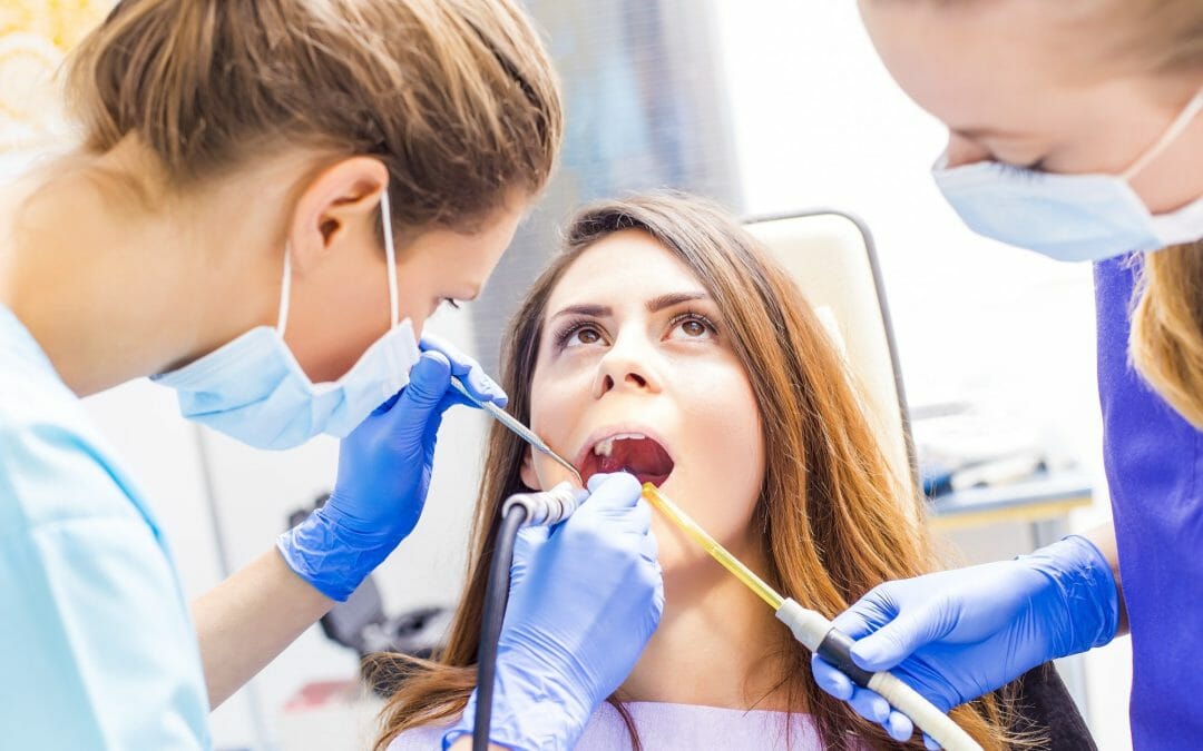 woman getting teeth cleaned and inspected at dentist office