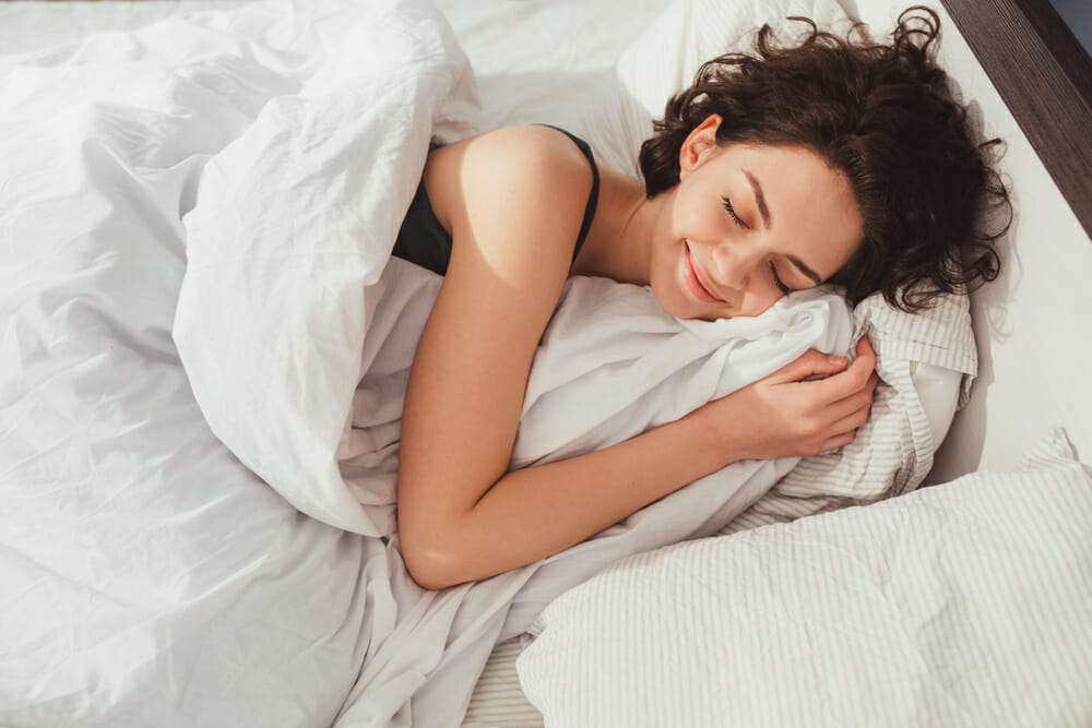 woman in comfortable bed smiling in her sleep